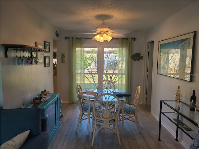 dining space with wood-type flooring, a textured ceiling, and ceiling fan