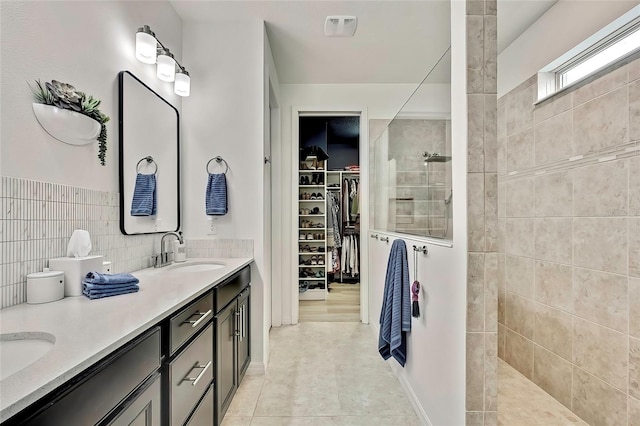 bathroom with tile walls, tile patterned flooring, a tile shower, and vanity