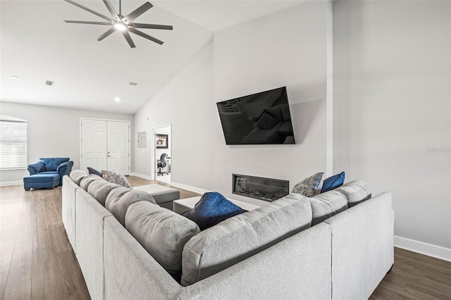 living room featuring ceiling fan, dark wood-type flooring, and high vaulted ceiling