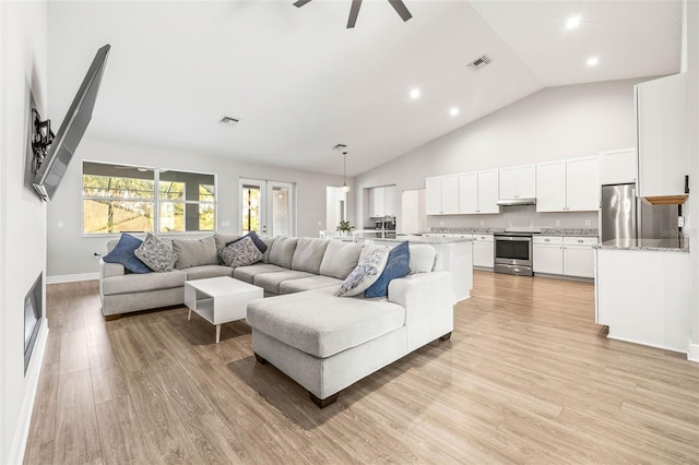 living room featuring ceiling fan, high vaulted ceiling, and light hardwood / wood-style flooring