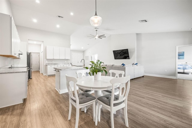 dining space with high vaulted ceiling, sink, light hardwood / wood-style flooring, and ceiling fan