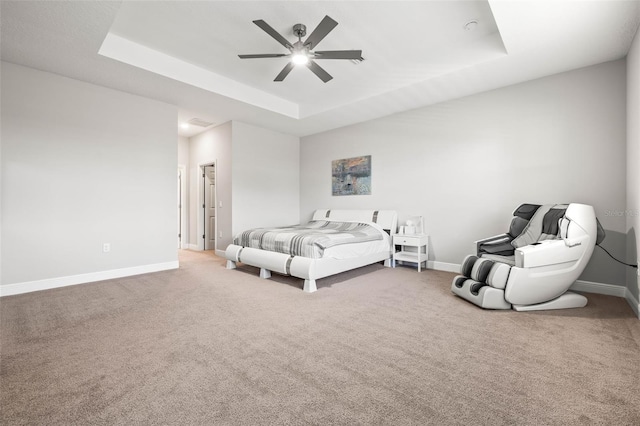 carpeted bedroom with a raised ceiling and ceiling fan