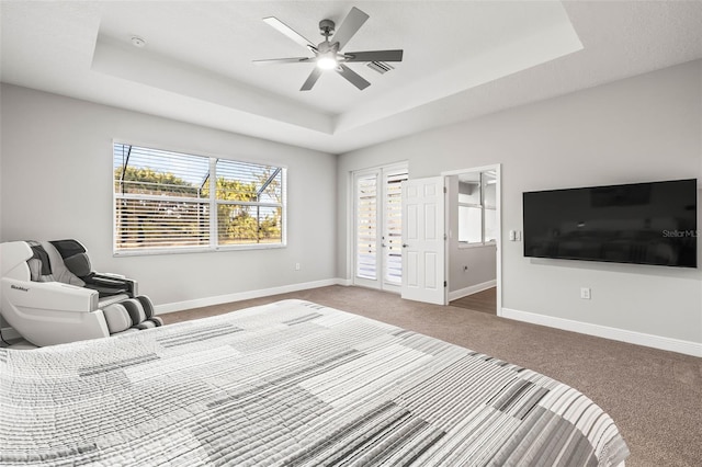 bedroom with ceiling fan, carpet flooring, access to outside, and a tray ceiling