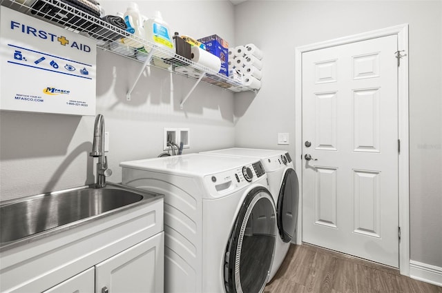 clothes washing area featuring cabinets, washer and clothes dryer, dark hardwood / wood-style flooring, and sink