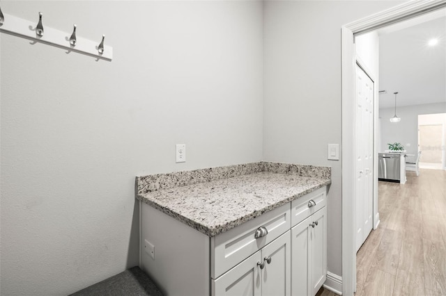 interior space with light stone countertops, white cabinetry, and light hardwood / wood-style floors