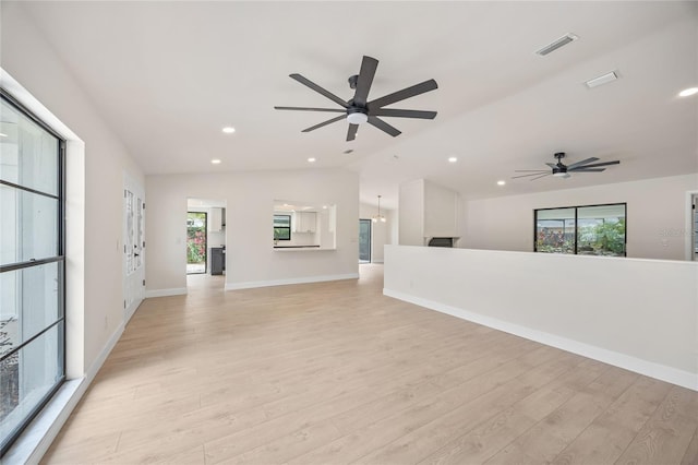 interior space with ceiling fan, vaulted ceiling, and light wood-type flooring