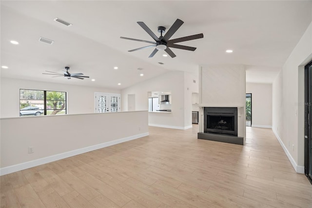 unfurnished living room with vaulted ceiling, ceiling fan, a fireplace, and light hardwood / wood-style flooring