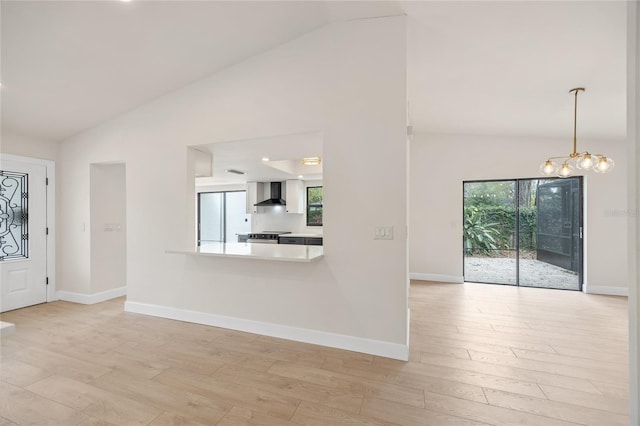 foyer entrance featuring lofted ceiling, light wood-type flooring, plenty of natural light, and an inviting chandelier