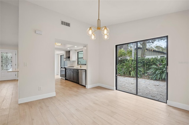 interior space featuring light hardwood / wood-style floors, sink, lofted ceiling, and a chandelier