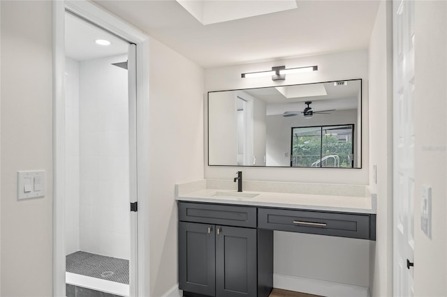 bathroom with ceiling fan, tiled shower, and vanity