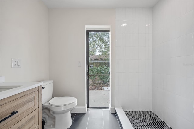 bathroom featuring tile patterned floors, toilet, vanity, and a tile shower