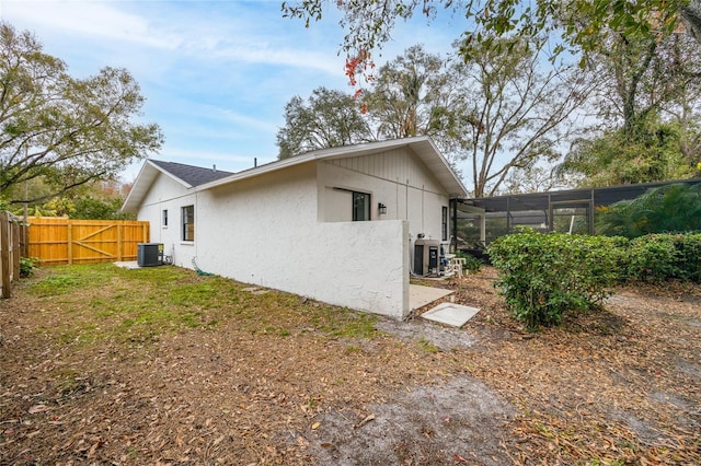 view of home's exterior with a lanai, central AC unit, and a yard