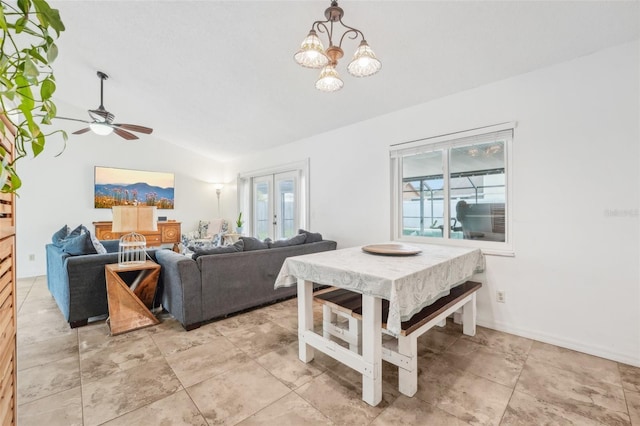 dining area featuring ceiling fan with notable chandelier, french doors, and vaulted ceiling