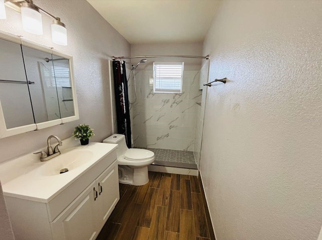 bathroom with a tile shower, vanity, and toilet