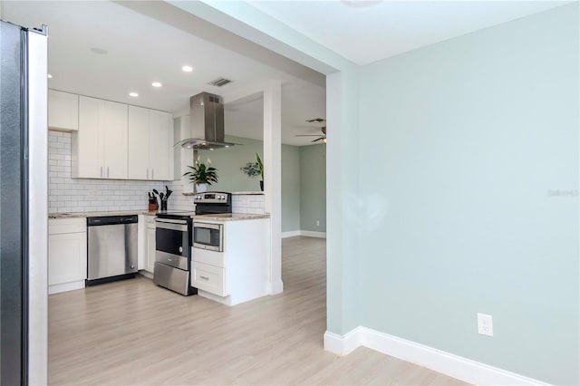 kitchen featuring island range hood, appliances with stainless steel finishes, decorative backsplash, white cabinets, and light hardwood / wood-style flooring