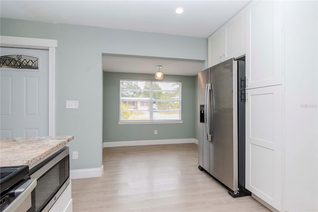 kitchen with stainless steel appliances, decorative light fixtures, white cabinetry, and light hardwood / wood-style flooring