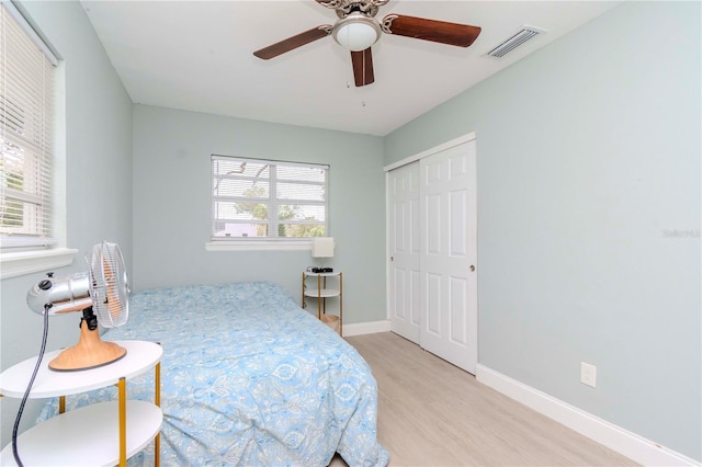 bedroom featuring ceiling fan, light wood-type flooring, a closet, and multiple windows