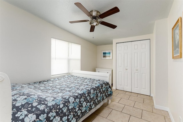 bedroom featuring light tile patterned floors, ceiling fan, baseboards, and a closet