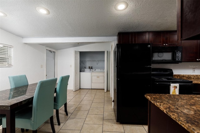 kitchen featuring a textured ceiling, dark stone countertops, light tile patterned floors, washer and dryer, and black appliances