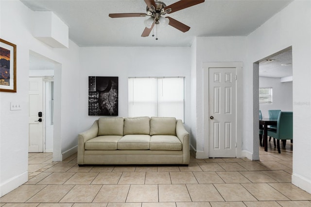 living room with a textured ceiling, ceiling fan, and light tile patterned floors