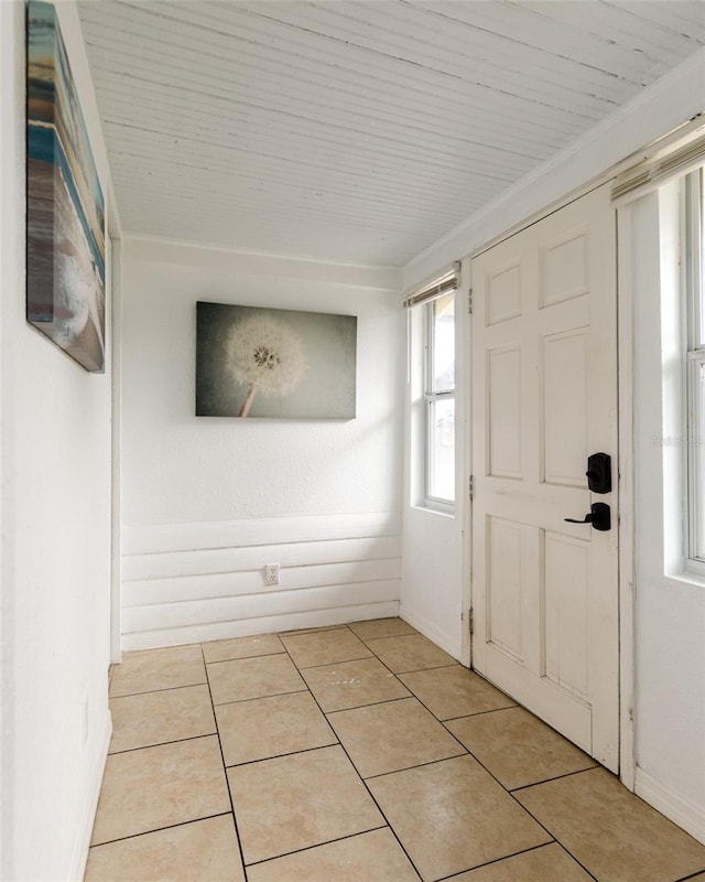 foyer entrance with crown molding and light tile patterned flooring