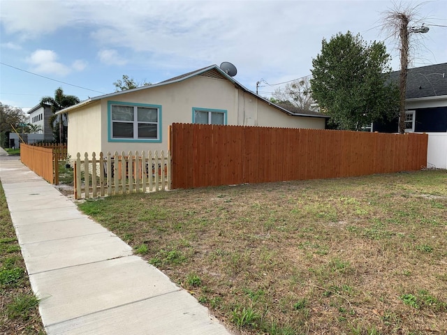 view of home's exterior featuring a yard, fence, and stucco siding