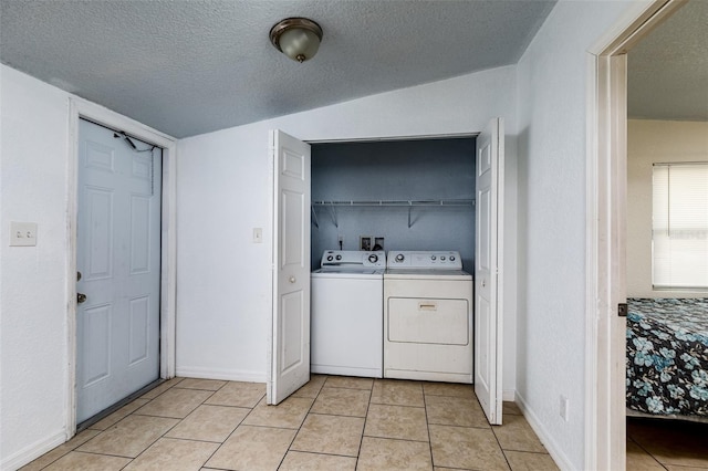 clothes washing area featuring light tile patterned floors, baseboards, laundry area, a textured ceiling, and washing machine and dryer