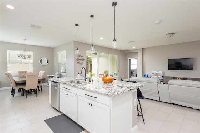 kitchen featuring dishwasher, white cabinetry, sink, light stone counters, and a center island with sink