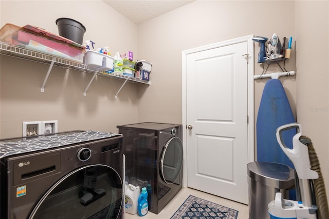 washroom featuring a textured ceiling, tile patterned floors, and washing machine and clothes dryer