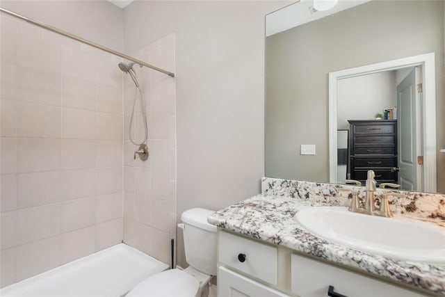 bathroom with toilet, vanity, and tiled shower