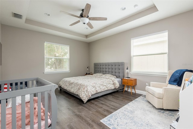 bedroom featuring ceiling fan, hardwood / wood-style floors, and a tray ceiling