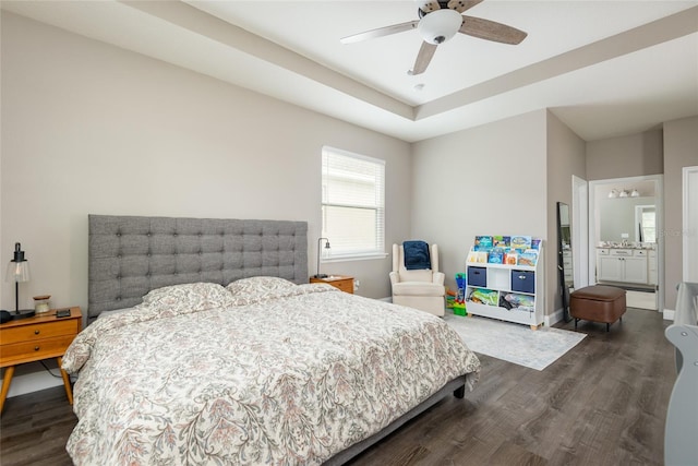 bedroom featuring ceiling fan, dark hardwood / wood-style flooring, connected bathroom, and a tray ceiling