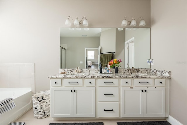 bathroom with tile patterned floors, a washtub, and vanity