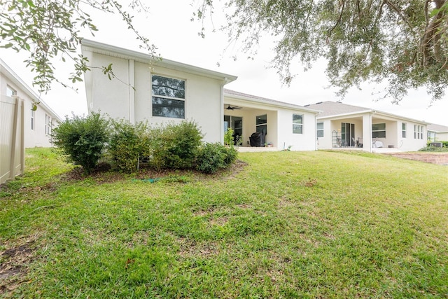 rear view of house with ceiling fan and a yard