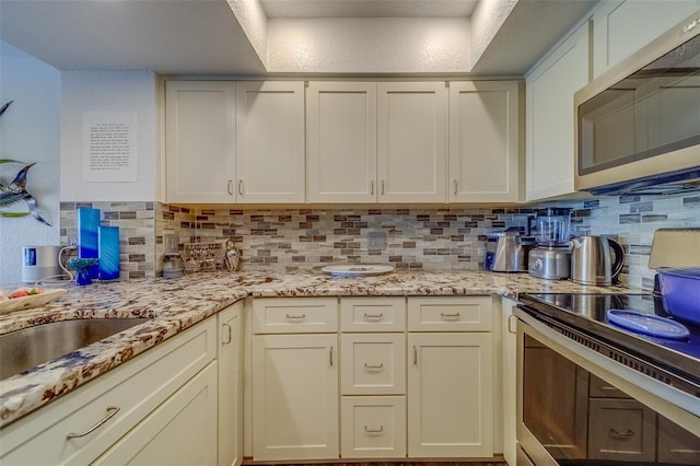 kitchen with stainless steel appliances, tasteful backsplash, and light stone counters