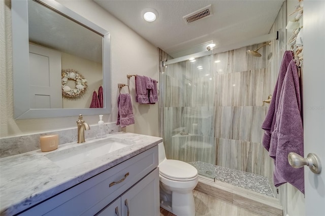 bathroom featuring toilet, an enclosed shower, a textured ceiling, and vanity