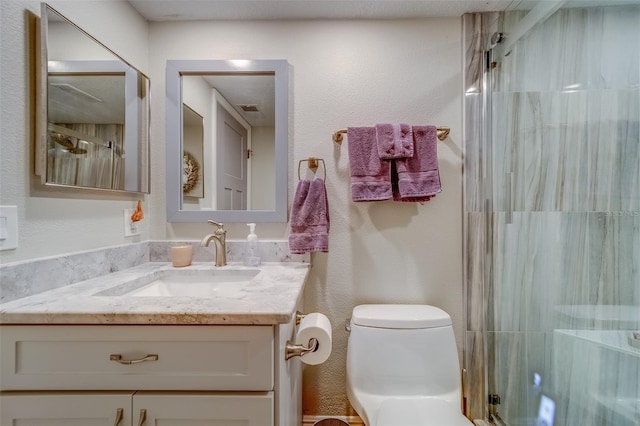 bathroom featuring a shower with door, vanity, and toilet