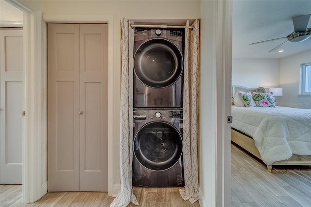 laundry room featuring ceiling fan, light hardwood / wood-style flooring, and stacked washer / drying machine