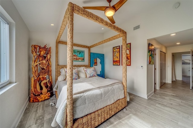 bedroom with ceiling fan, light hardwood / wood-style floors, and vaulted ceiling