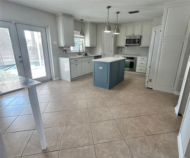 kitchen featuring a center island, decorative light fixtures, stainless steel appliances, light tile patterned floors, and sink