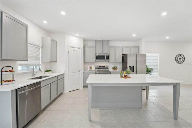 kitchen with sink, a kitchen island, gray cabinets, and appliances with stainless steel finishes