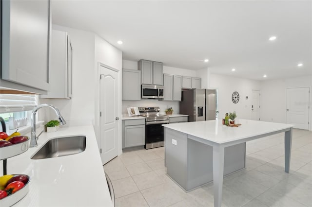 kitchen with sink, a kitchen island, gray cabinets, and appliances with stainless steel finishes