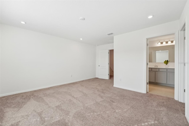 unfurnished bedroom with sink, light colored carpet, and connected bathroom