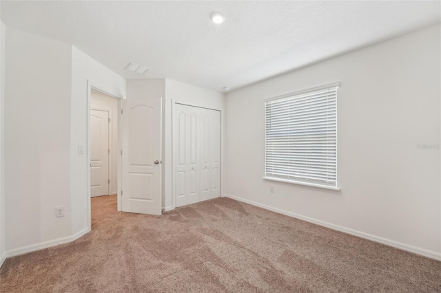 unfurnished bedroom featuring a closet and light carpet