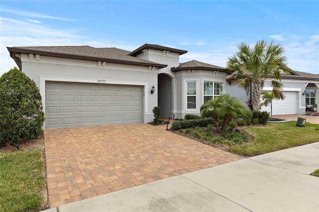 view of front of home with an attached garage, decorative driveway, and stucco siding