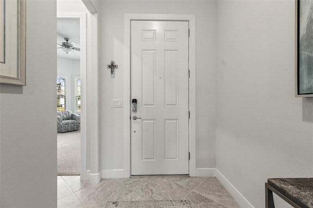 entryway featuring light tile patterned flooring, a ceiling fan, and baseboards