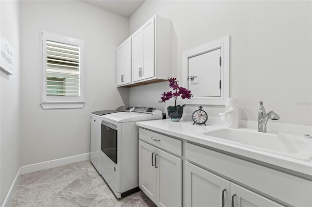 washroom with washer and dryer, cabinet space, a sink, and baseboards