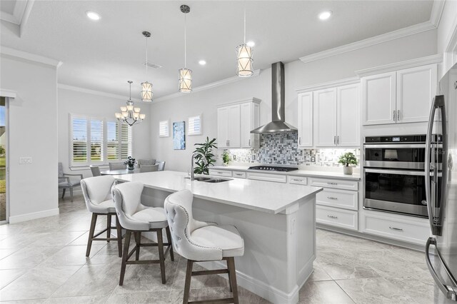 kitchen with tasteful backsplash, appliances with stainless steel finishes, ornamental molding, a sink, and wall chimney range hood