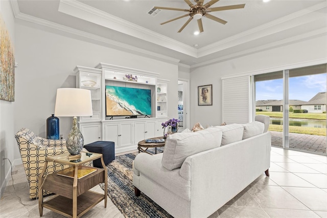 living area with ornamental molding, a raised ceiling, visible vents, and a ceiling fan