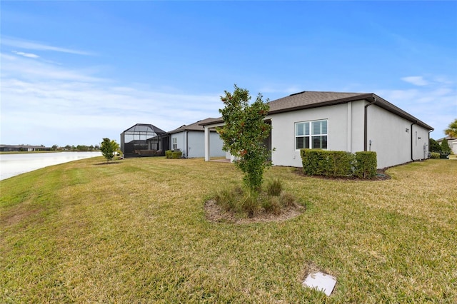 exterior space featuring a water view, a lawn, and stucco siding